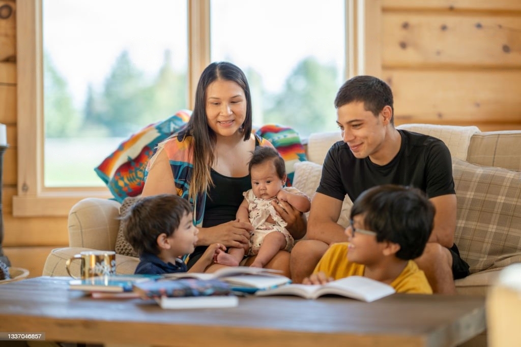 Indigenous mother and father sitting and playing with their children in their living room